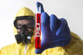 Man in full personal protective equipment with vial of blood and Ebola written on it